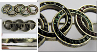 Schne Silberbrosche in Form der Olympischen Ringe mit eingesetzten farbigen Strasssteinen und verzierten Fassungsrndern, 4x1,5 cm.<br>-- Schtzpreis: 125,00  --
