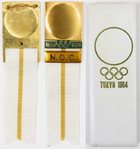Offizielles Teilnehmerabzeichen "N.O.C." (Nationales Olympisches Komitee) fr die Olympischen Spiele Tokyo 1964. Bronze, vergoldet. Schriftleiste orange emailliert. Seidenband in wei-gelb. 14x3,8cm. In Originaletui.