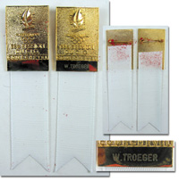 2x Offizielles Teilnehmerabzeichen der "98e Session du C.I.O. Courchevel" (1992). Bronze vergoldet, farbig emailliert, weies Seidenband. 11,3x3 cm, in original Box (Plastik, 12x4x1,5 cm). Ein Abzeichen mit dem Namen des Trgers "W.Troeger".<br>-- Schtzpr